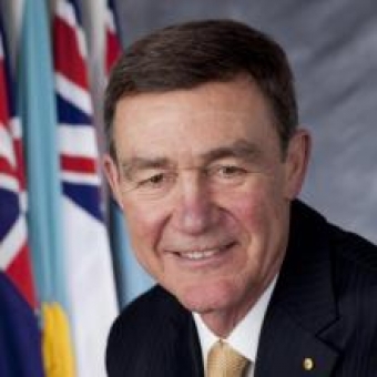 portrait picture of Air Chief Marshal Sir Angus Houston with flags in background