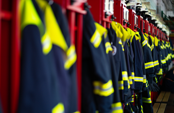 Firefighters' suits lined up in a firestation. 